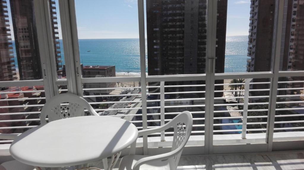 a table and chairs in a room with a view of the ocean at Apartamentos Los Caballos in Benidorm