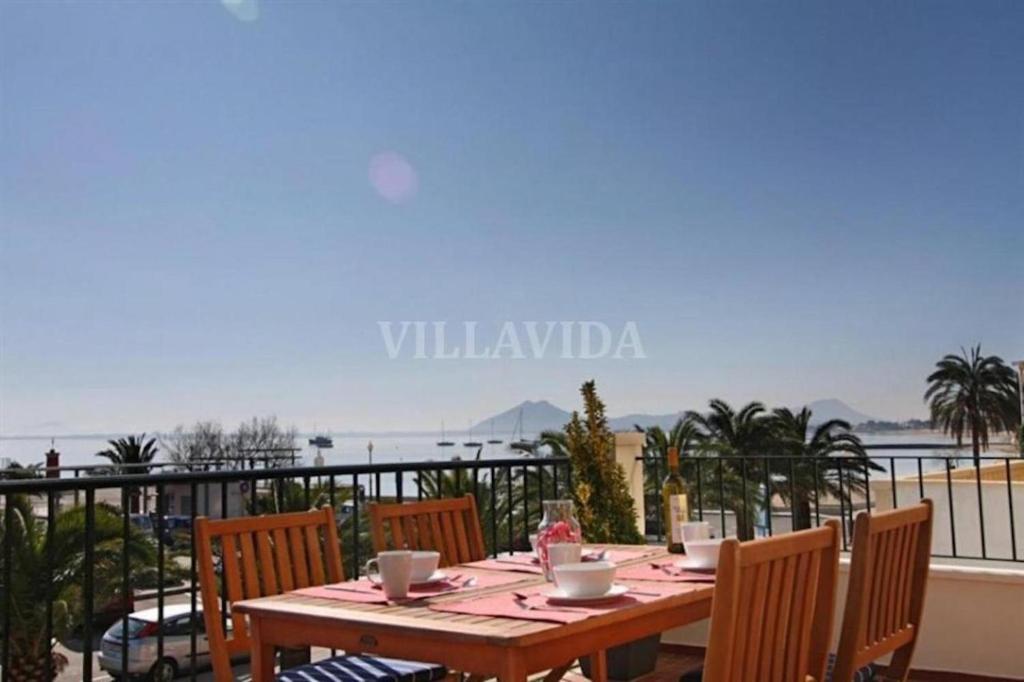 a wooden table with chairs and a view of the ocean at Seafront Marina 1 Apartment in Pollença