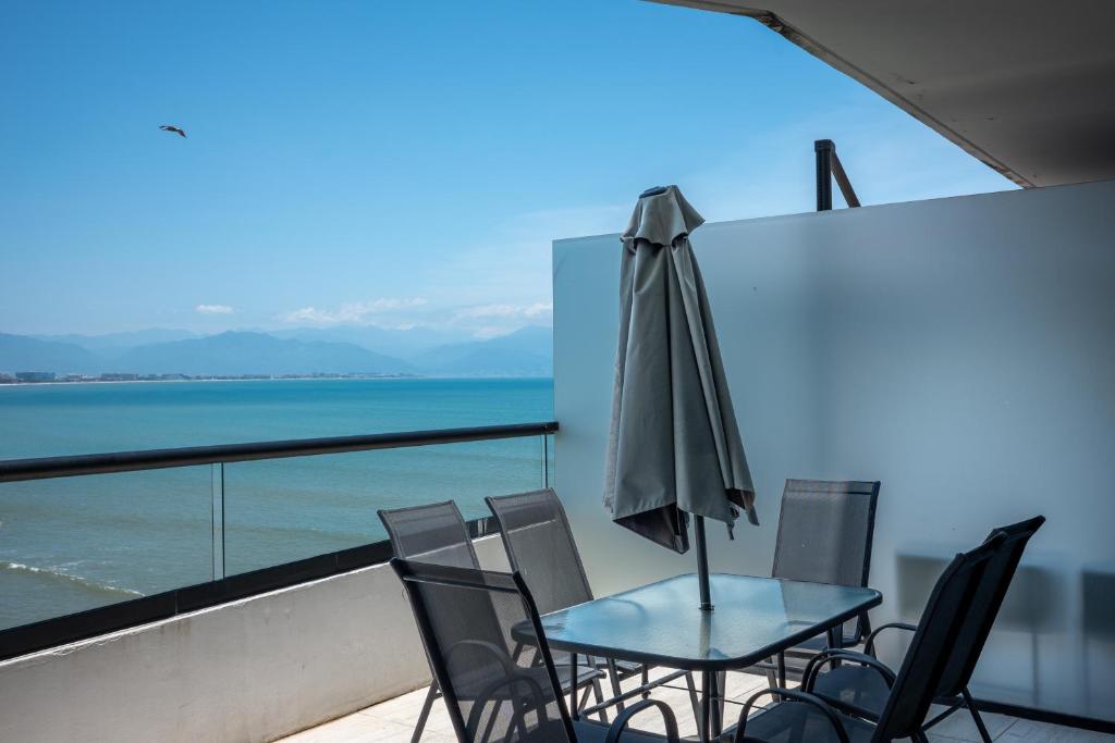 a table and chairs with an umbrella on a balcony at Condo in Bucerías Beachfront Narval Norte in Bucerías