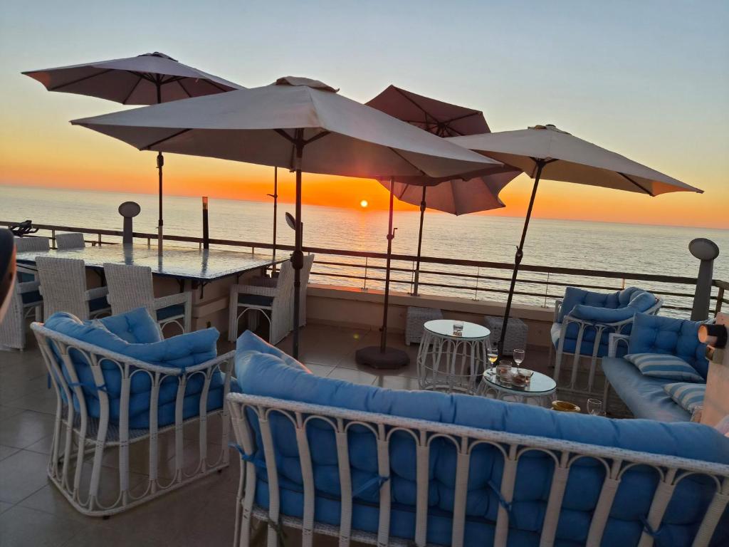 a patio with chairs and tables and umbrellas at Best Sea View in Morocco in Sidi Bouqnadel