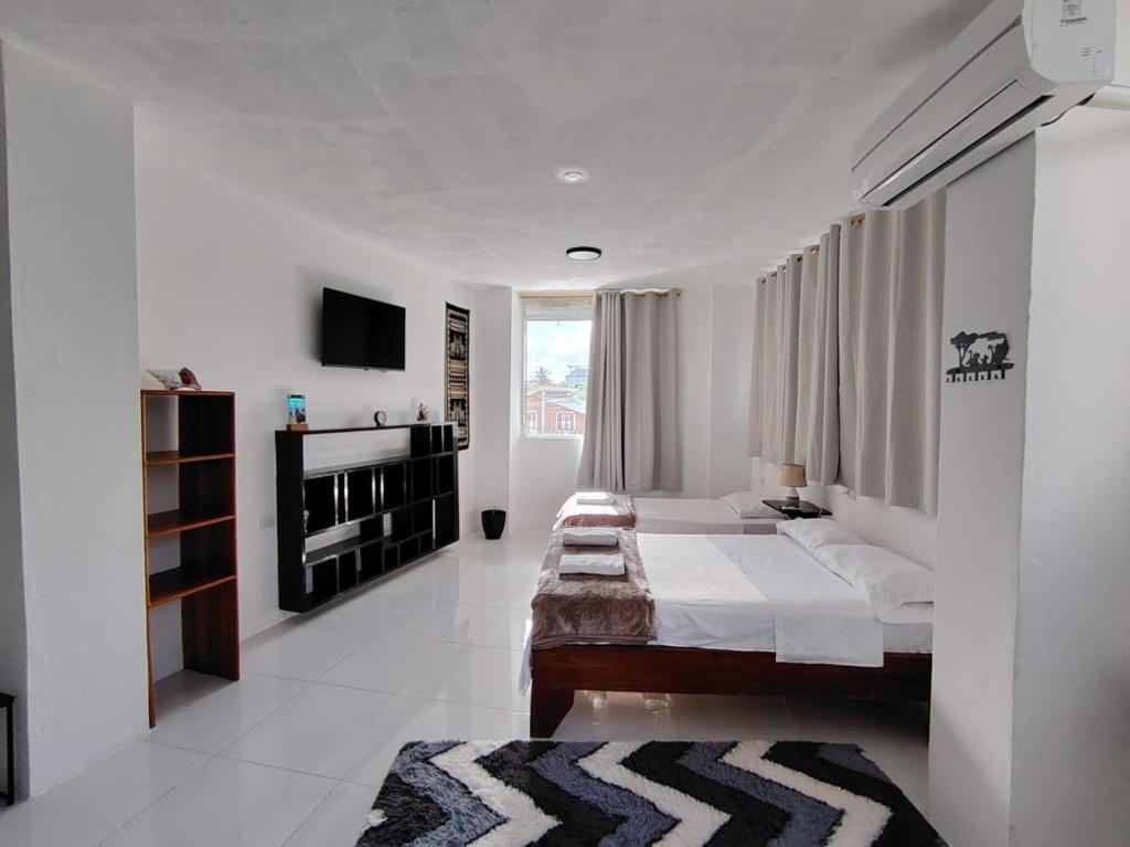 a white room with a bed and a television at Galápagos Apartments in Puerto Ayora