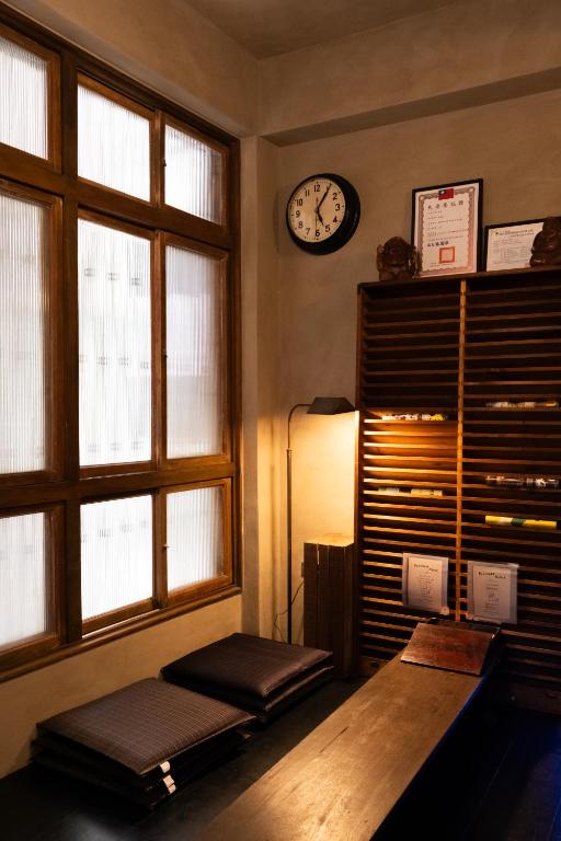 a room with a table and a clock on the wall at sishi hostel 巳時旅宿 in Tainan