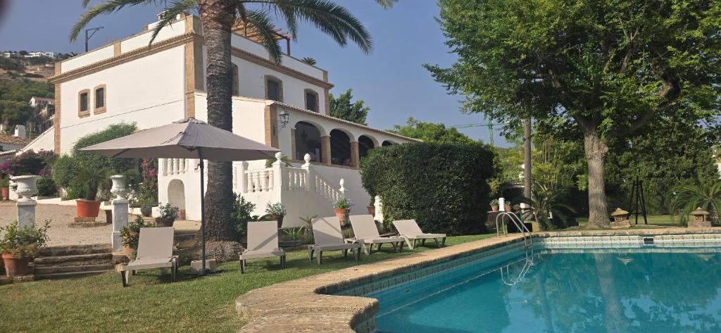 a pool with chairs and an umbrella in front of a building at Mezquida del puerto in Jávea