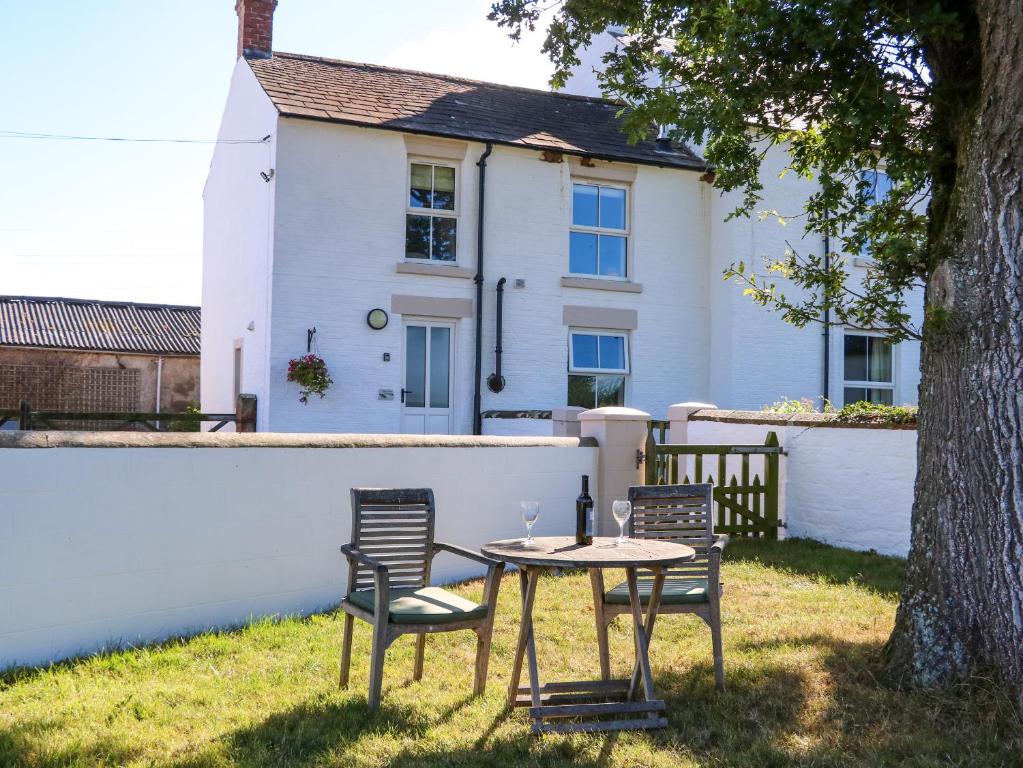 a table and chairs in front of a house at Tight Lyne Cottage in Carlisle