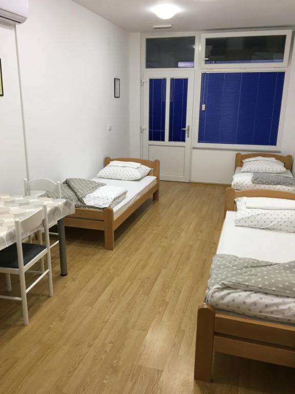 a room with four beds and a table and windows at Rooms Prišlin in Bjelovar