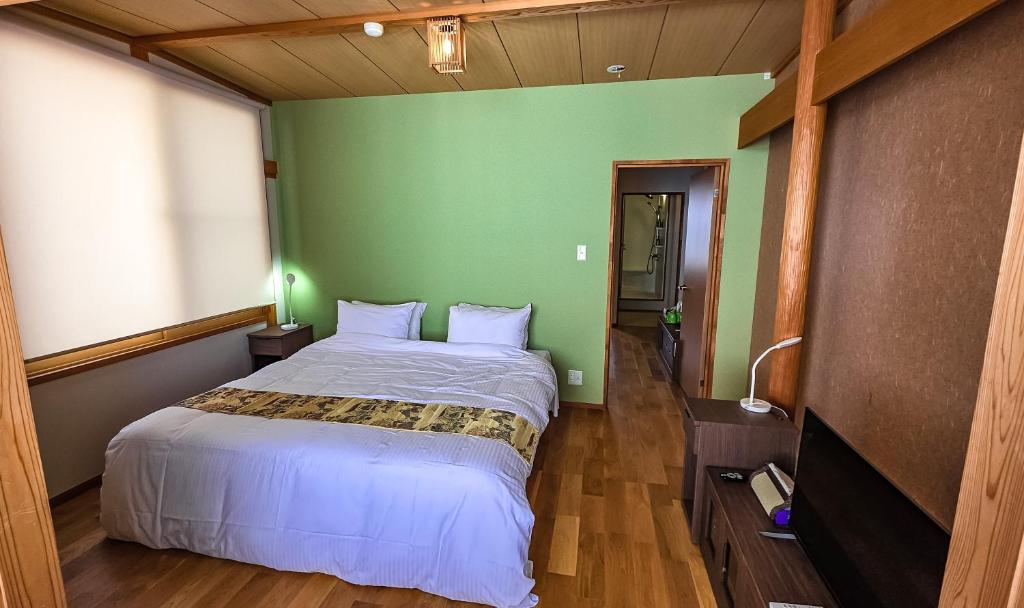 a bedroom with a bed with a green wall at Komatsuya Seki Onsen in Myoko