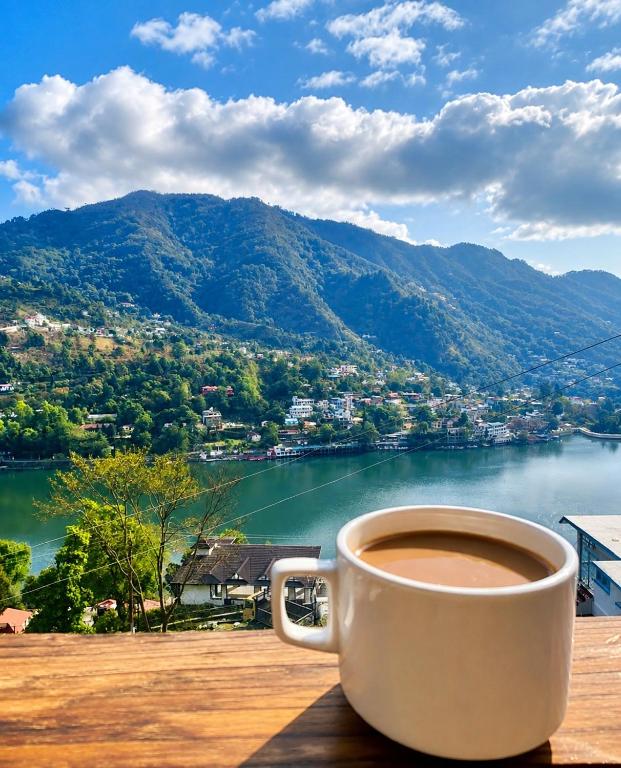 a cup of coffee sitting on a table overlooking a lake at The Shantii Boho in Bhīm Tāl