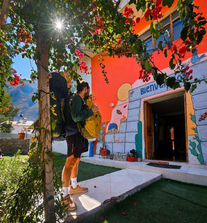 a man with a backpack standing in front of a building at Valle verde, Hostel & camping in Urubamba