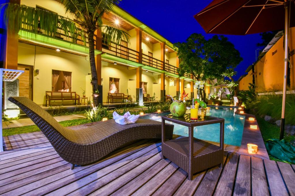 a deck with a couch and a table and an umbrella at The Rani Garden Bed & Breakfast in Denpasar