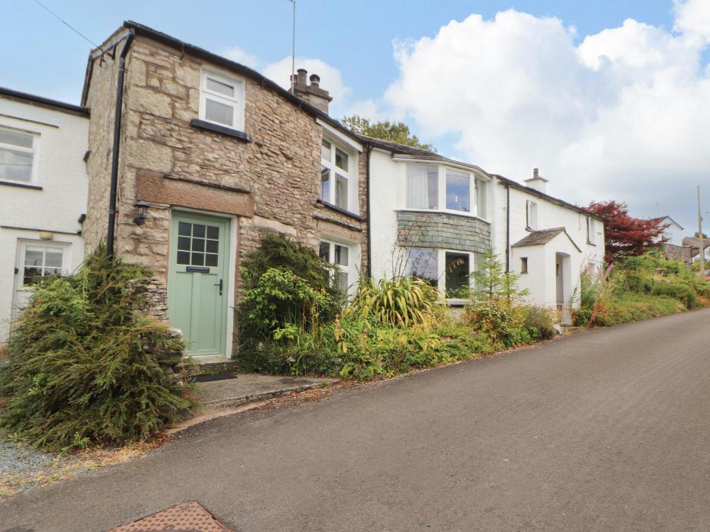 an old brick house with a green door on a street at The Orchard in Kendal