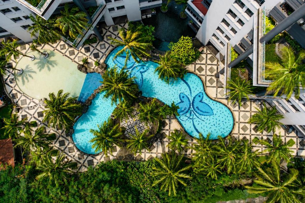 an overhead view of two swimming pools with palm trees at Grand Tropic Suites Hotel in Jakarta