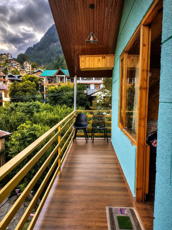 a wooden porch with a chair on top of a house at Jain Residency in Manāli