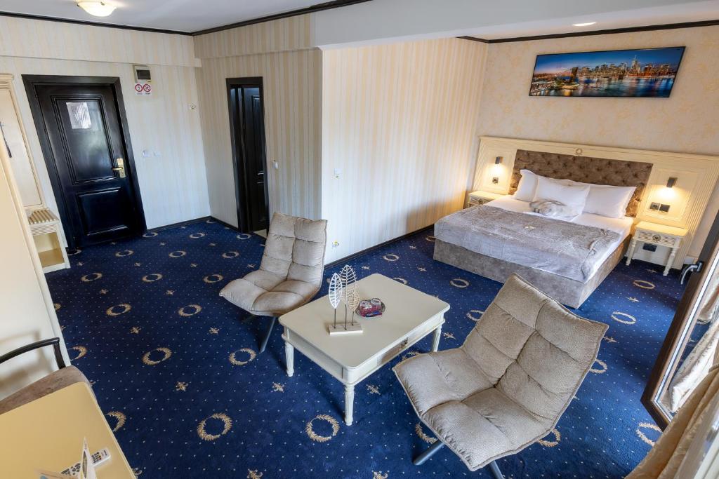 a hotel room with a bed and a table and chairs at Hotel Ambasador Iasi in Valea Lupului
