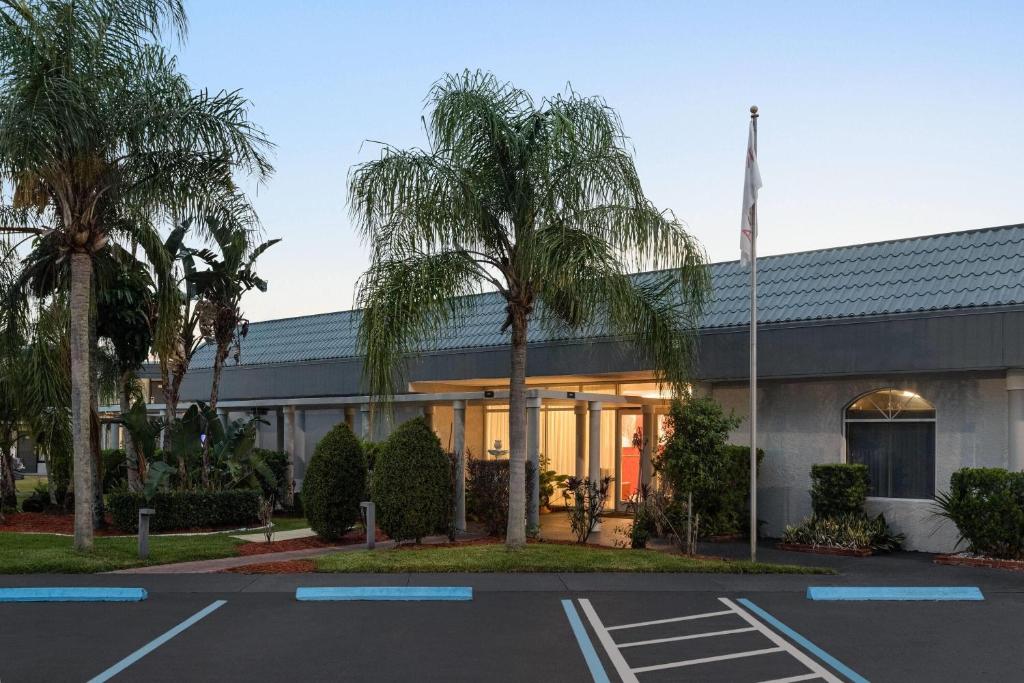 a building with palm trees in a parking lot at Ramada by Wyndham Cocoa in Cocoa