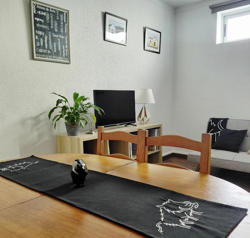a living room with a table and a cat sitting on a rug at De Cá - suite com acesso independente e kitchenette in Lousã