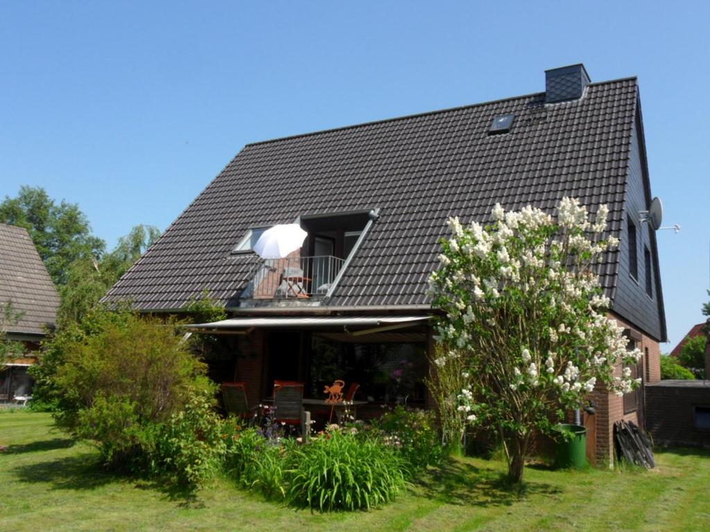 uma casa com um telhado preto e um jardim em Appartement bei Kiel em Lilienthal