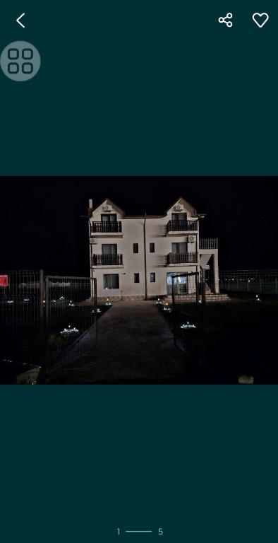 a large white building in a parking lot at night at Pensiunea LA ANI in Vadu