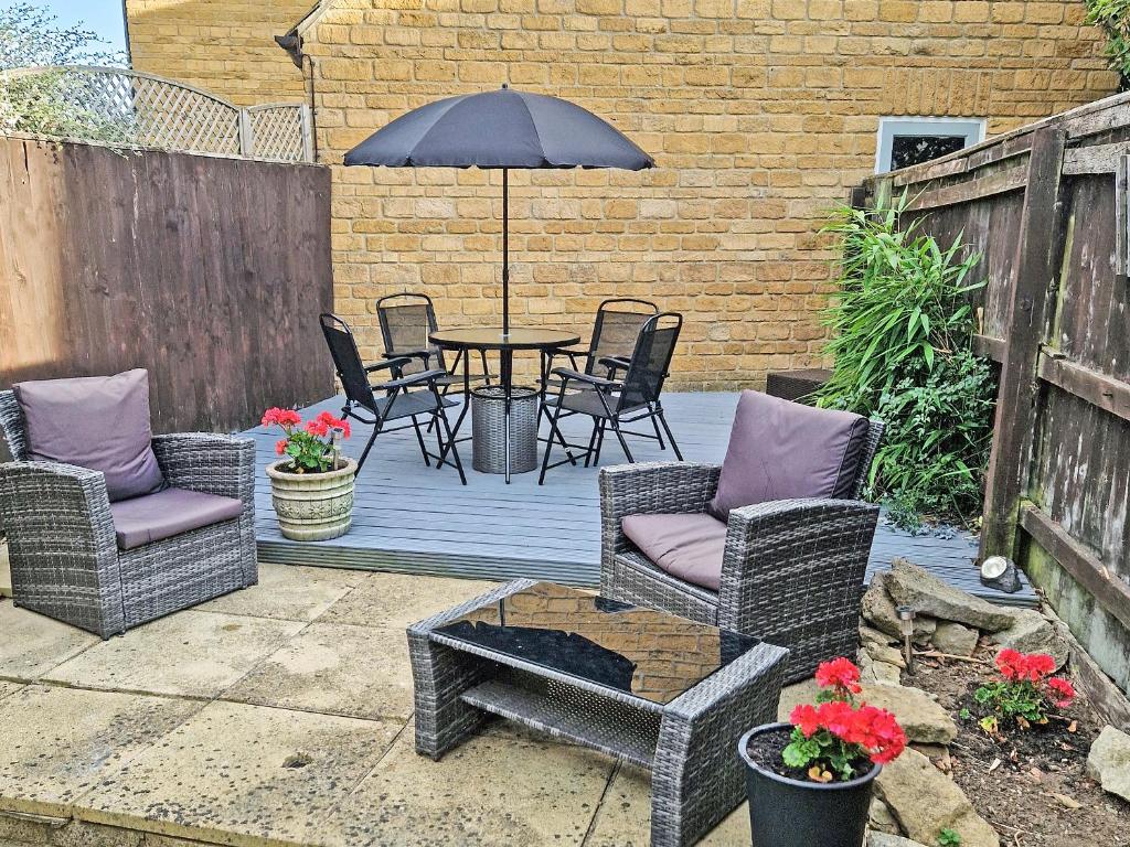 a patio with chairs and a table with an umbrella at Jasmine Cottage in Chipping Campden