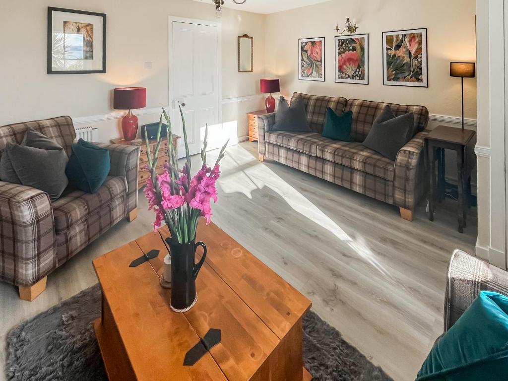 a living room with couches and a table with flowers on it at 10 The Apostles - Uk37312 in Lochranza