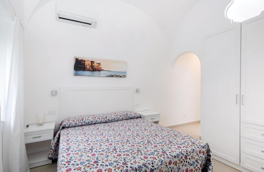 a white bedroom with a bed and a painting on the wall at Villa Pollio Guest House in Anacapri