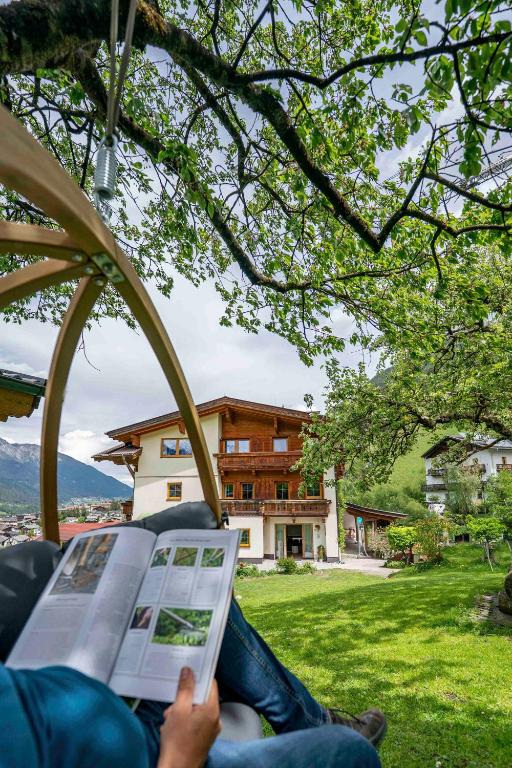 a person sitting in a chair reading a newspaper at Untersillerhof in Neustift im Stubaital