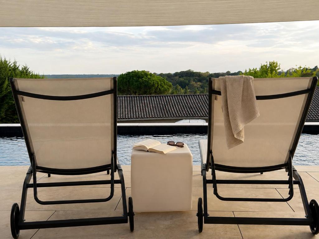 two chairs sitting on a porch by the water at L'Escapade Caramanaise in Caraman