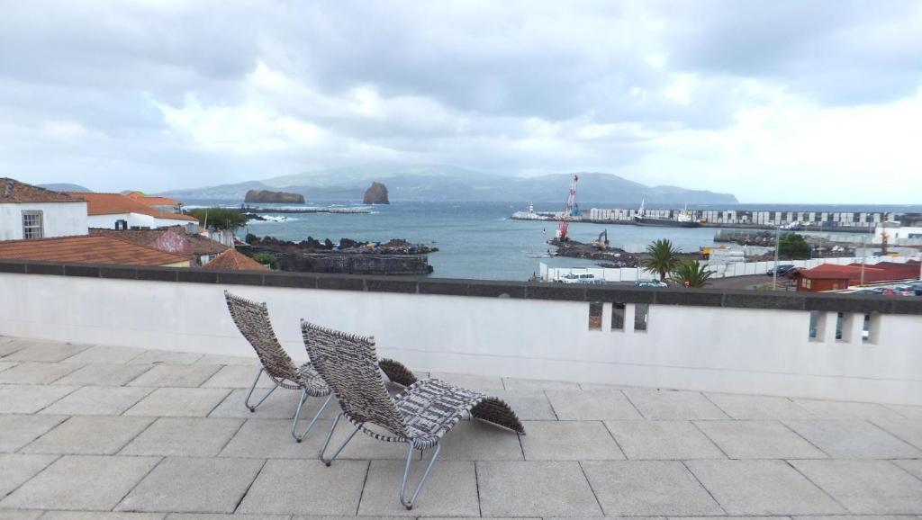 two chairs sitting on a balcony looking at the ocean at Casa do Pico Madalena in Madalena