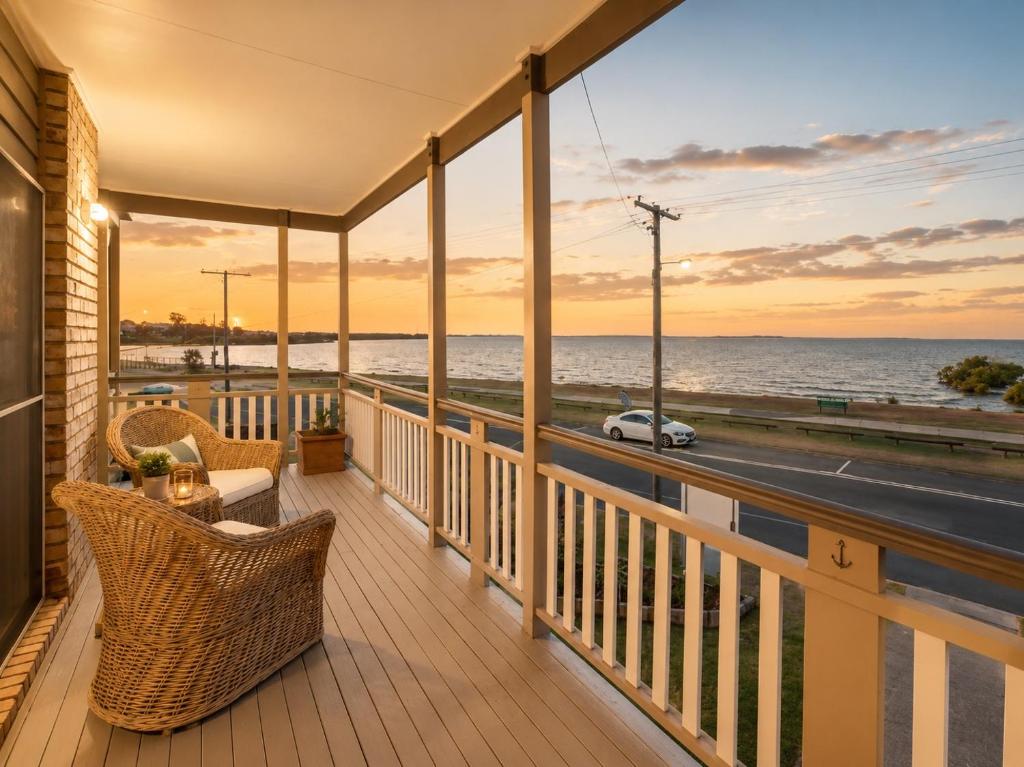 a balcony with wicker chairs and a view of the ocean at Stunning Sea Facing Bayside House with Pool in Birkdale