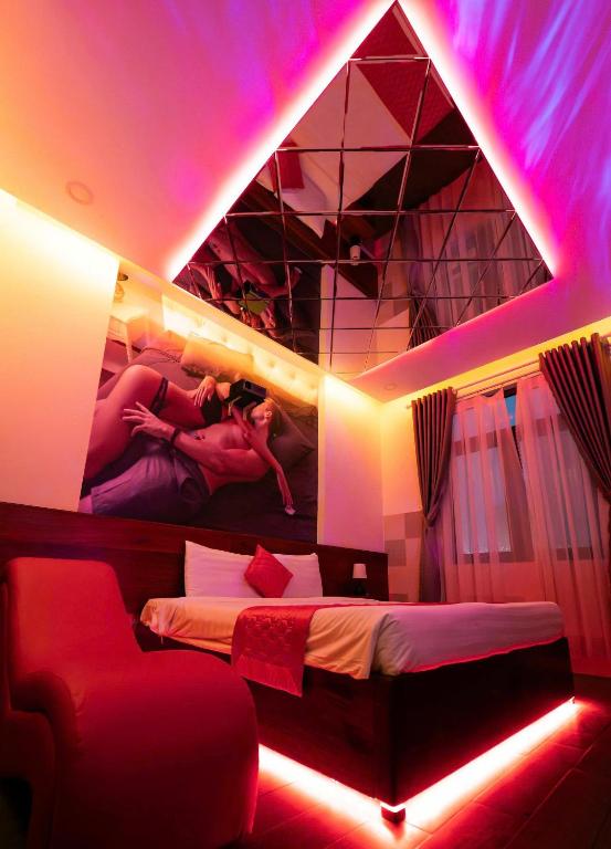 a room with a bed and a painting on the wall at Đào Hoa Mộng Couple Hotel - Central & City View in Quy Nhon