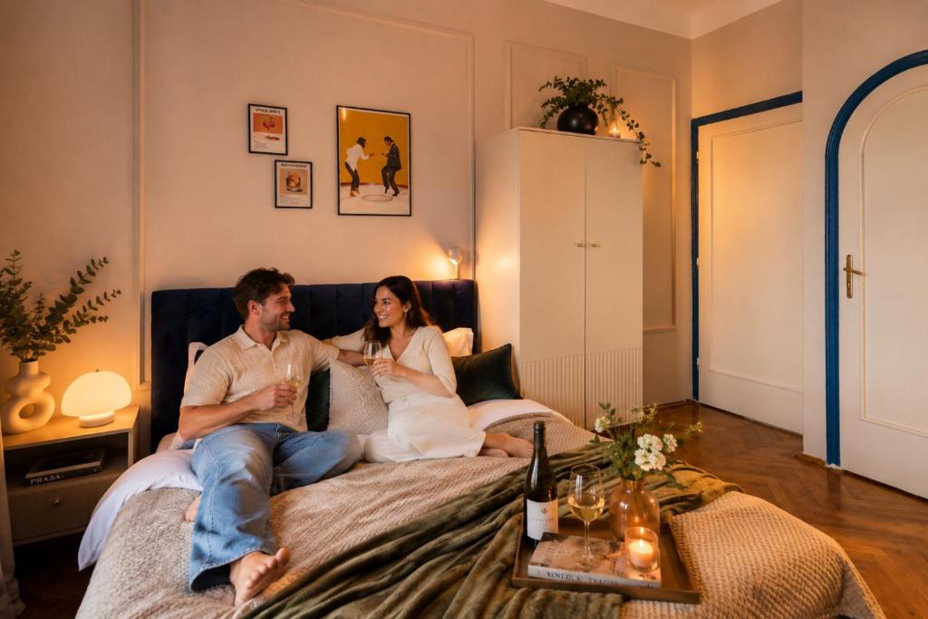 a man and woman sitting on a bed with drinks at Decebal Modern Studio - Central Arad in Arad