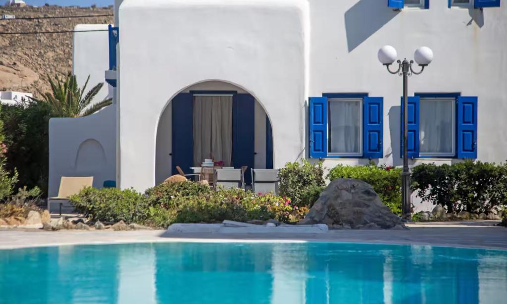 a building with blue windows and a swimming pool at Mykonian Style w Shared Pool Houses 8 & 9 in Ornos
