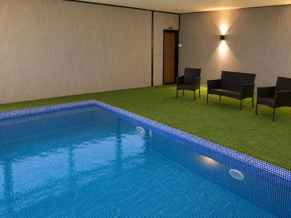 a swimming pool in a room with chairs and a table at בית ההר - וילה למשפחות עם בריכה פרטית in Rama