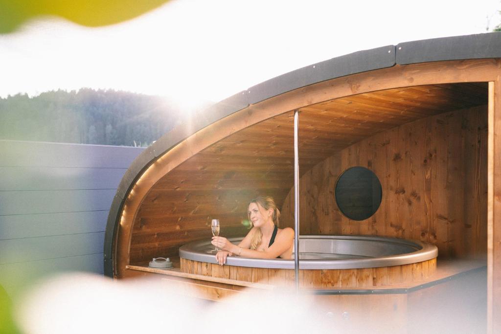 a woman sitting in a bath tub with a glass of wine at Ferienbahnhof Fichtental Bahnhofs-Apartment in Prackenbach