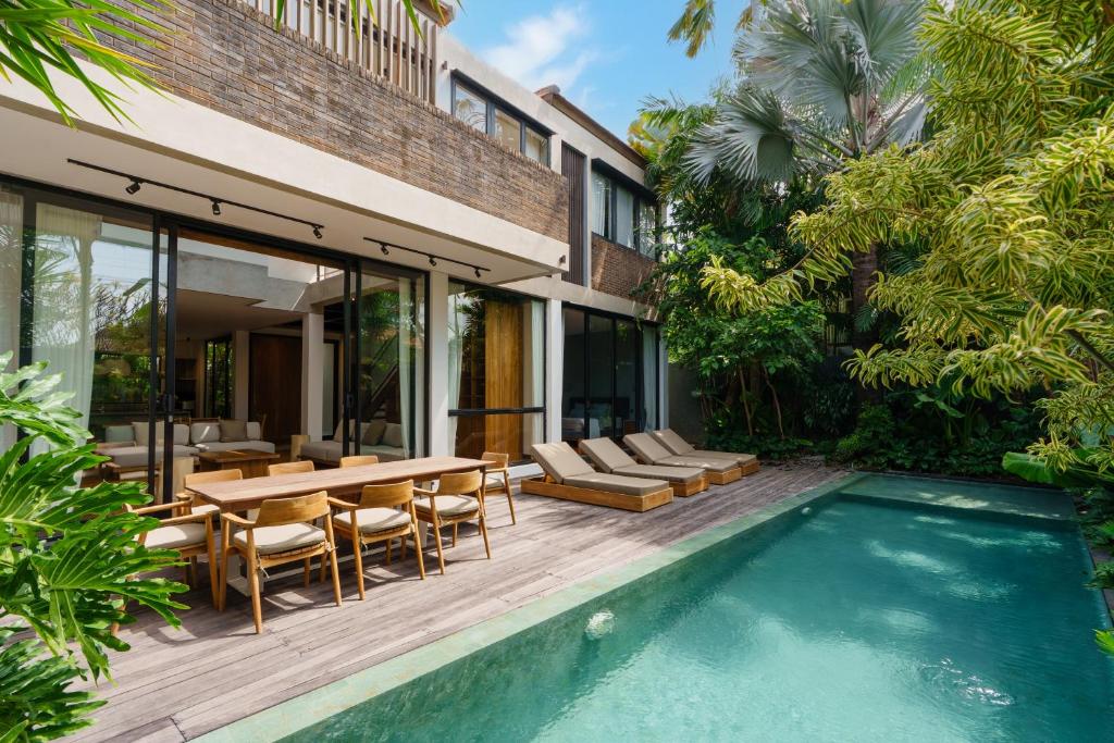 a patio with a table and chairs next to a pool at Villa Pakuk by Alfred in Bali in Canggu