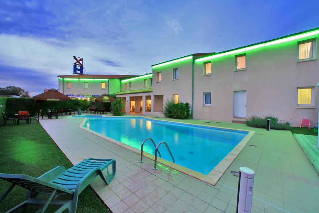 a swimming pool in front of a building at Logis Hôtel L'Air Marin in Yves