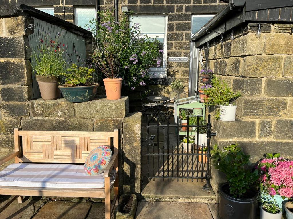 a bench sitting on a patio with potted plants at Snowdrop Cottage in Keighley