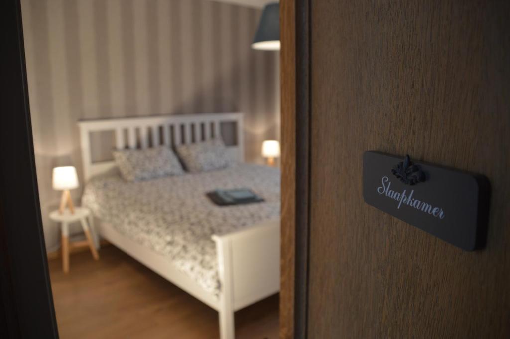 een slaapkamer met een wit bed en een deur met een spiegel bij De Staberg in Bilzen