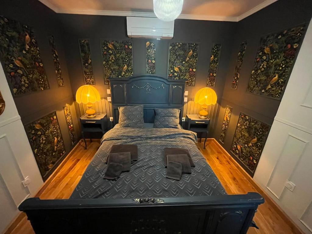 a bedroom with a black bed with two lamps on the wall at Le Rococo f2 climatisé plein centre in Monistrol-sur-Loire