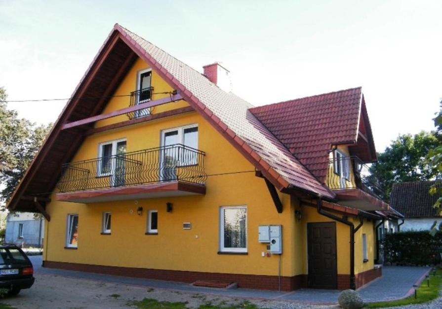 uma casa amarela com um telhado vermelho em Panterej Pokoje Gościnne em Kruklanki