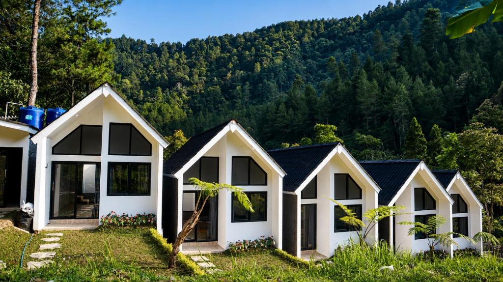 a row of white cottages in front of a mountain at ULYAKABIN Glamping Tawangmangu Private Pool Air Hangat Plus BBQ in Tawangmangu