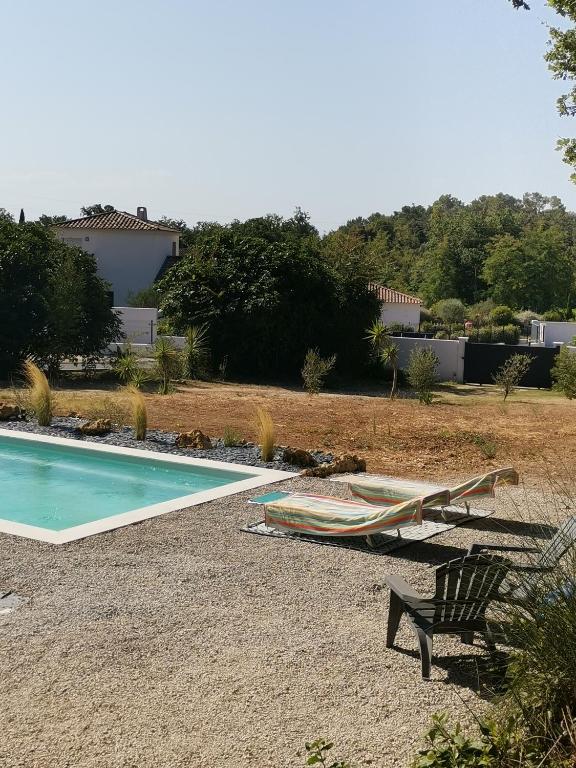 a hammock and a chair next to a swimming pool at Au domaine Isabelle in Lorgues