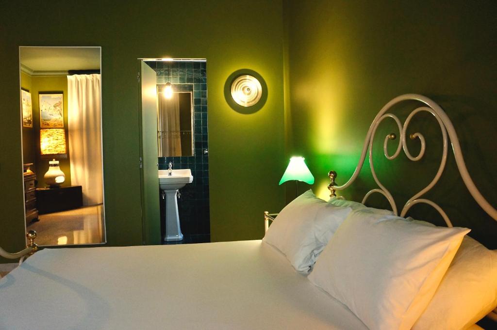 a bedroom with a white bed with a green wall at Kiwi in Latina