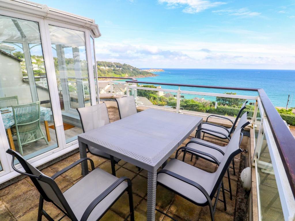 a table and chairs on a balcony with the ocean at Ocean Gem in Carbis Bay