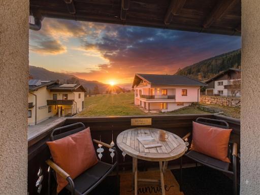 a balcony with a table and chairs and a sunset at Boutique73 Sunrise in Ossiach