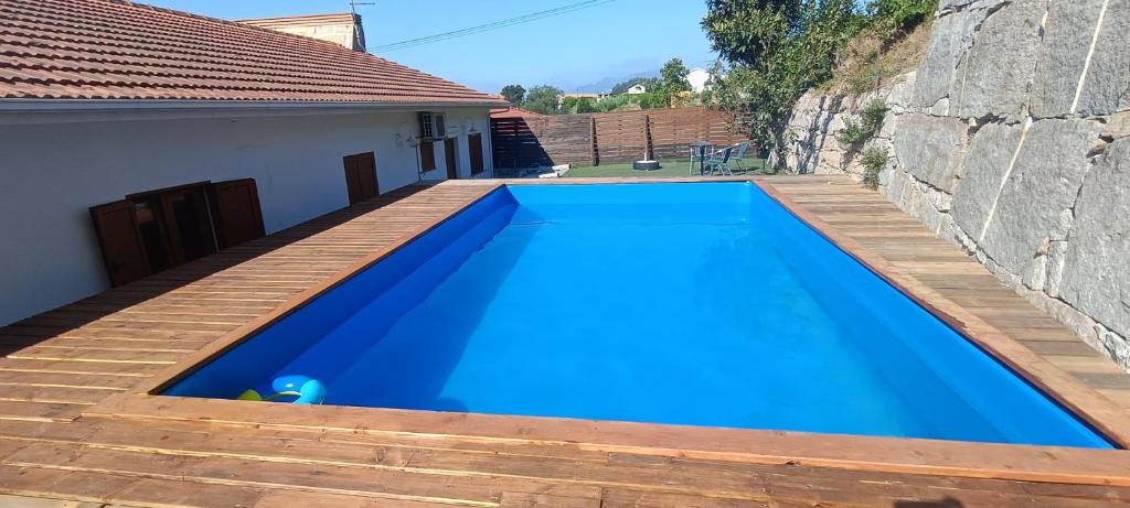 a blue swimming pool with a wooden deck at Casa do Casal do Douro in Marco de Canaveses