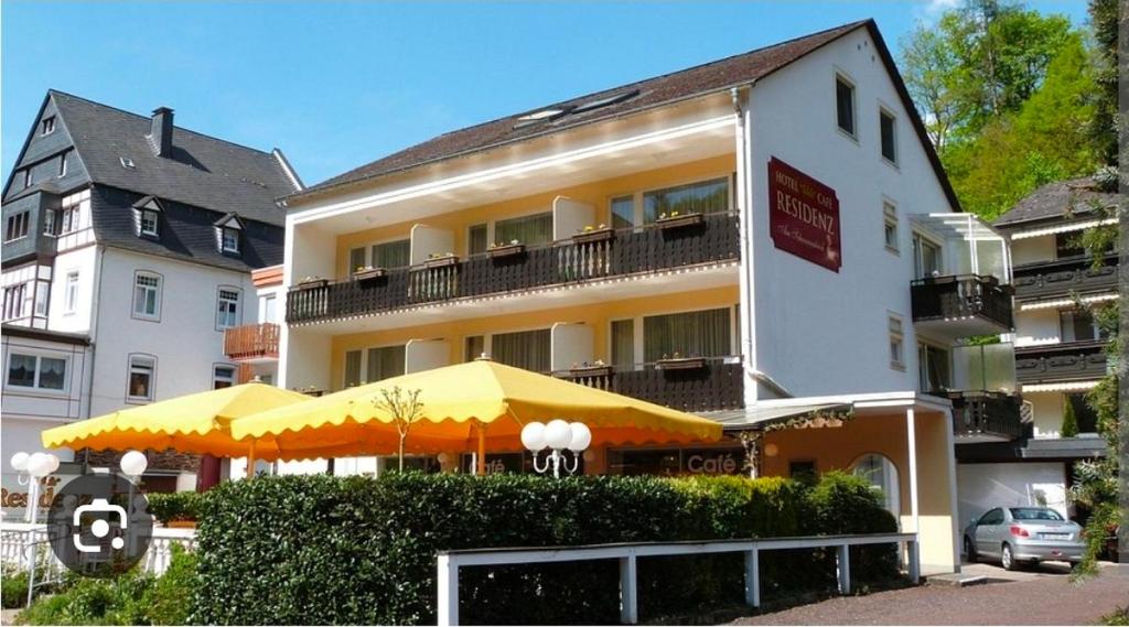 a building with a yellow umbrella in front of it at Hotel-Café Residenz Bad Bertrich in Bad Bertrich
