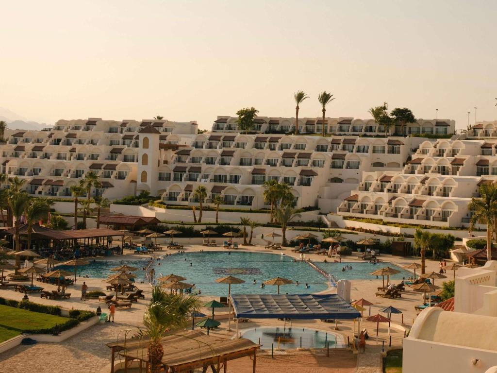 a large hotel with a swimming pool in front of a building at Movenpick Resort Sharm El Sheikh in Sharm El Sheikh