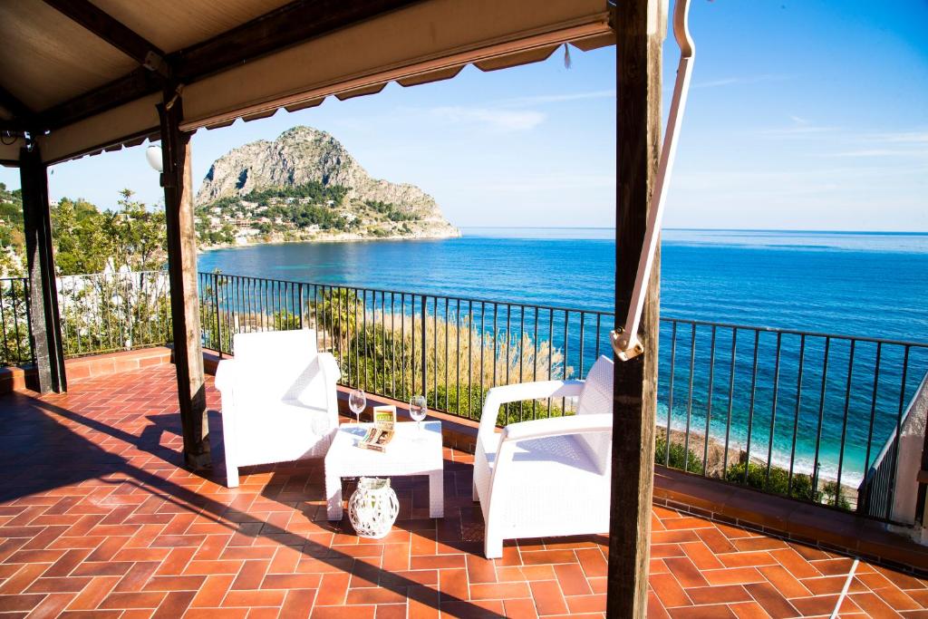 eine Veranda mit weißen Stühlen und Meerblick in der Unterkunft Villa Buonasera in Santa Flavia