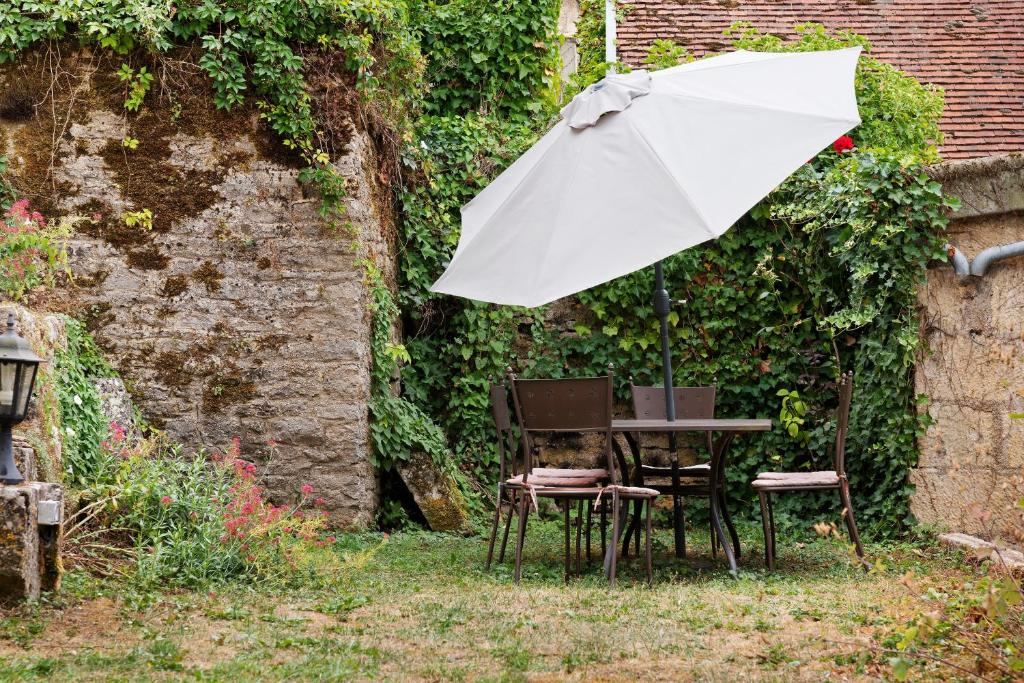 a table and chairs with an umbrella in a garden at B&B La Demoiselle in Aignay-le-Duc