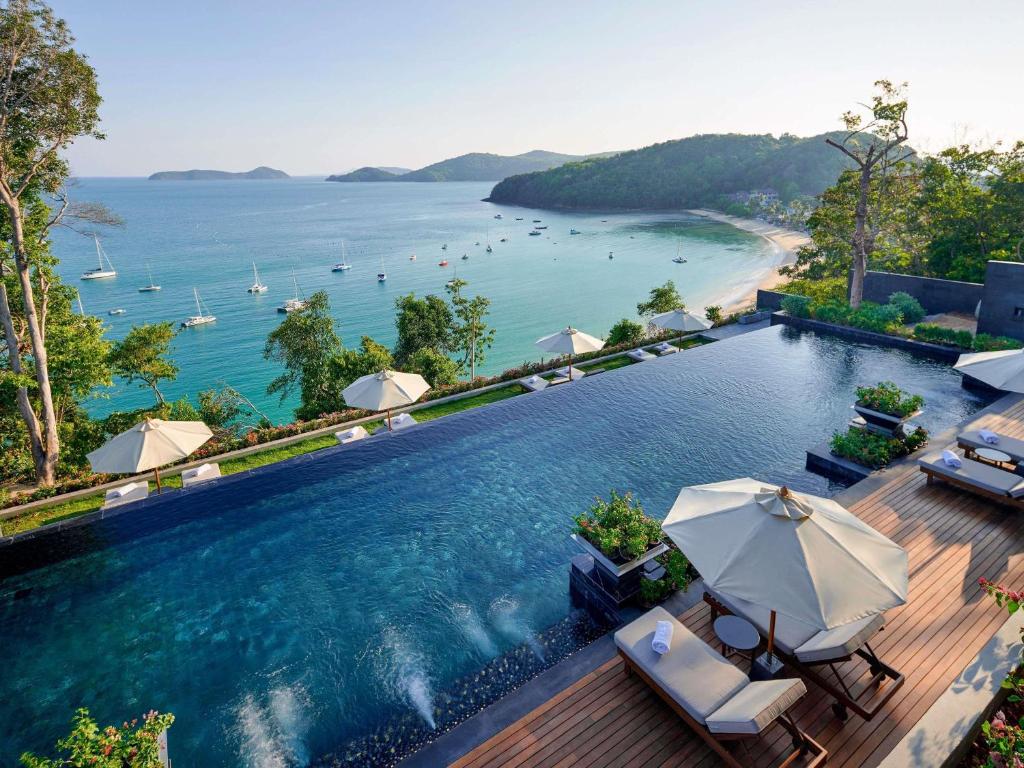 a swimming pool with umbrellas and a view of the ocean at V Villas Phuket - MGallery Collection in Panwa Beach